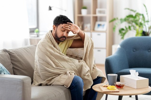 sick young man in blanket having headache or fever